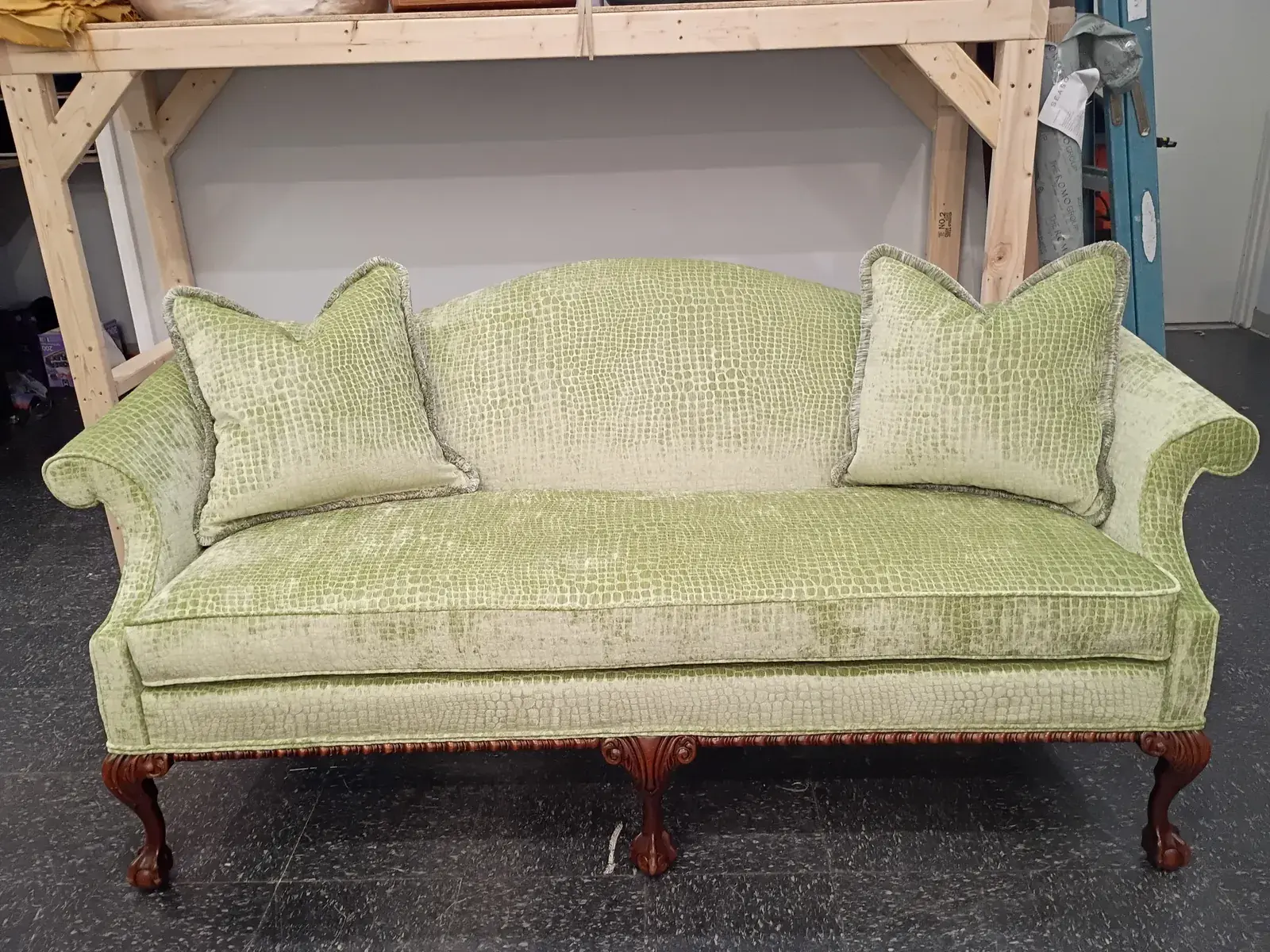 Camelback sofa in chartreuse velvet with matching pillows and carved wood legs