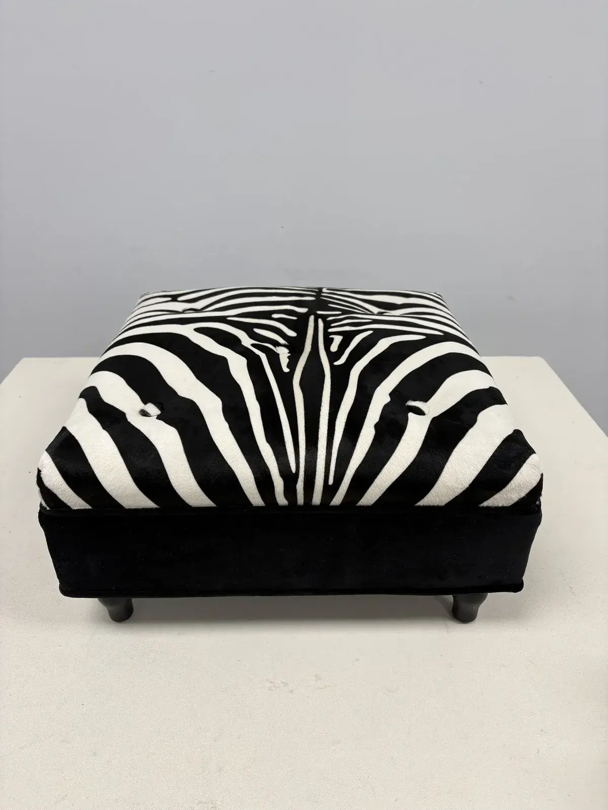 Zebra-print ottoman on a black base